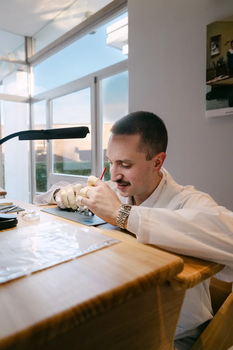 Une personne manipule une pièce horlogère à un établi pendant un atelier photographié par TimFocus