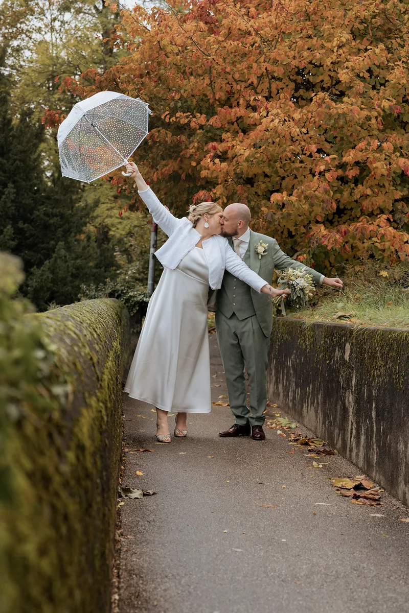 Mariés sous un parapluie devant les feuillages d’automne, photographie TimFocus