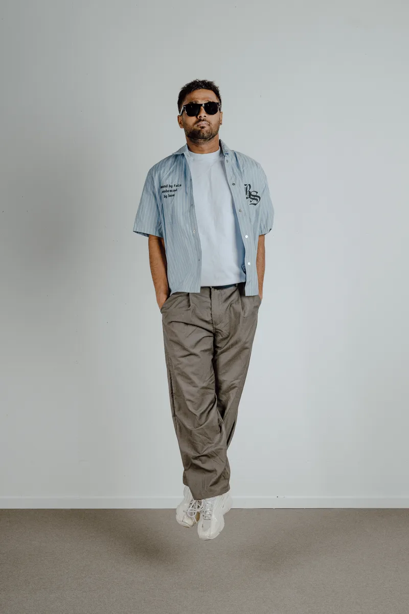 Portrait en pied d’un homme avec des lunettes de soleil devant un fond clair, photographie TimFocus